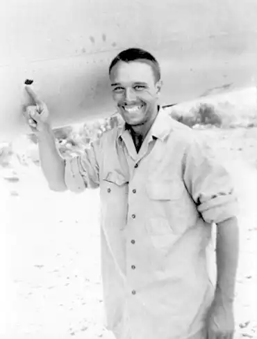 Quentin Kaiser pointing to Flak hole from July 15, 1944 mission #17 over Ferrara, Italy.